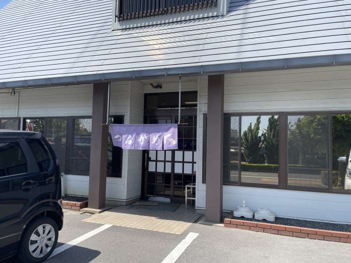 観音寺市にあるセルフ讃岐うどん店「つるかめうどん」さんの外観。紫色ののれんが目印の落ち着いた佇まい。