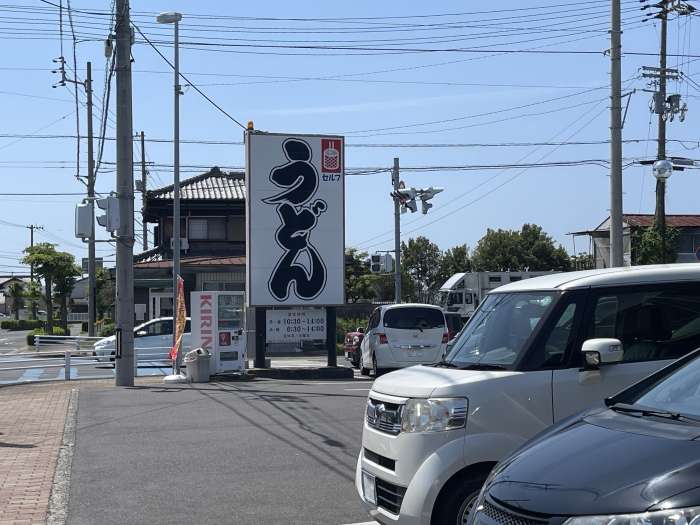 「うどん」と書かれたインパクトある看板が目印。「つるかめうどん」さんの店舗敷地内駐車スペースの様子。