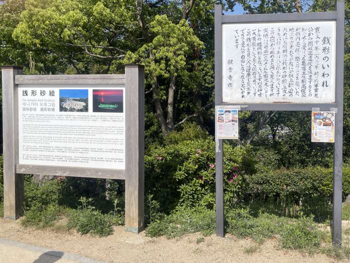 香川県観音寺市「琴弾公園」内にある銭形砂絵の由来と説明を記した案内板。観光客に人気の撮影スポット。